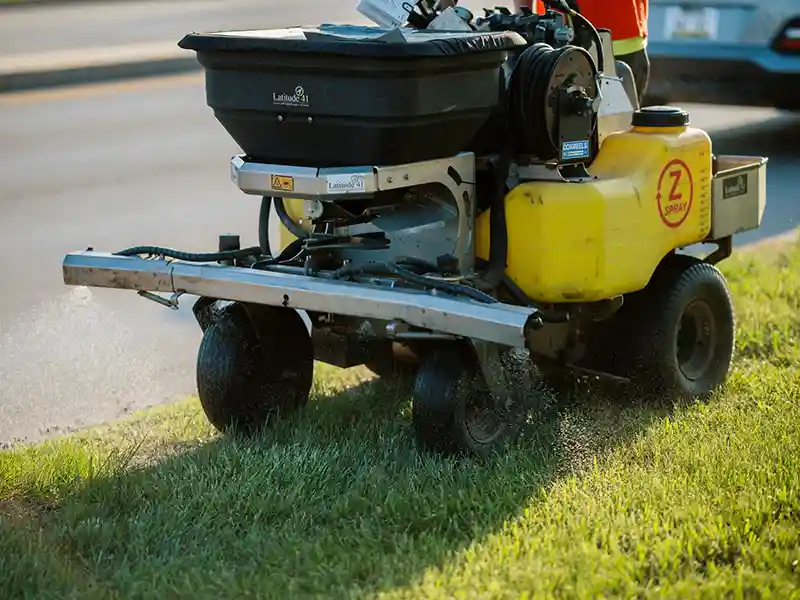 Machine spreading fertilizer on lawn
