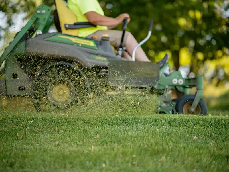 Worker mowing lawn